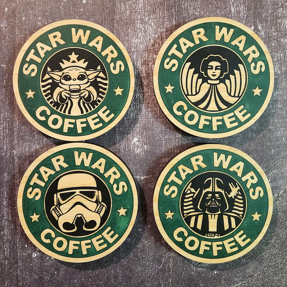 Four Star Wars coffee-themed coasters, engraved and hand-painted green, on a dark bench