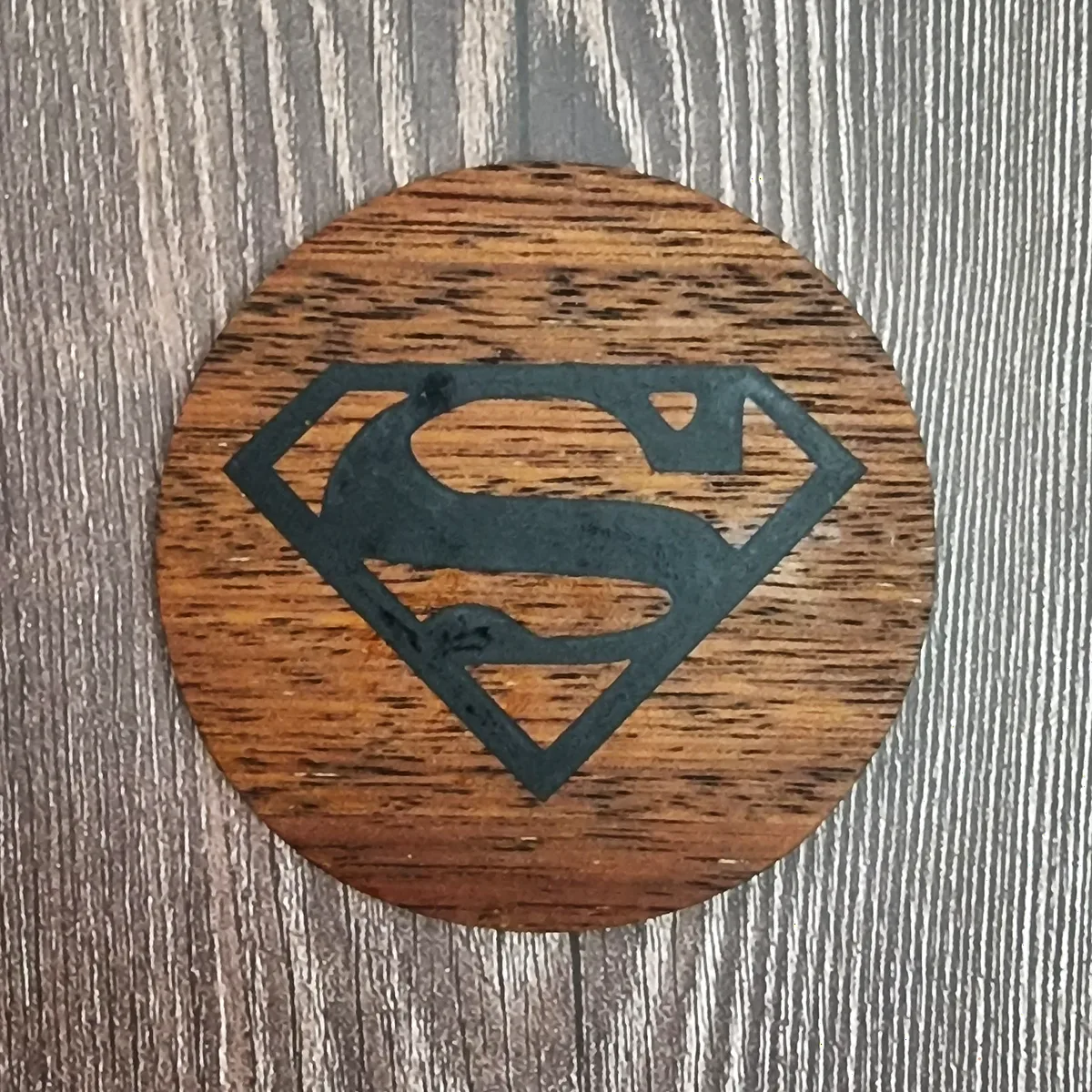 Dark timber coaster engraved with the Superman emblem in black